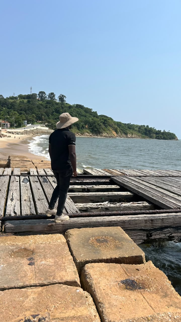 Visitante num cais de madeira a olhar a costa de Cabinda