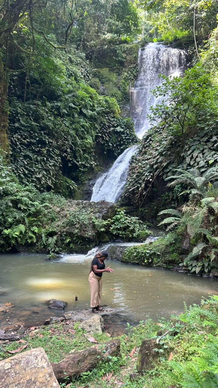 Visitante junto a uma cascata de dois níveis na floresta tropical